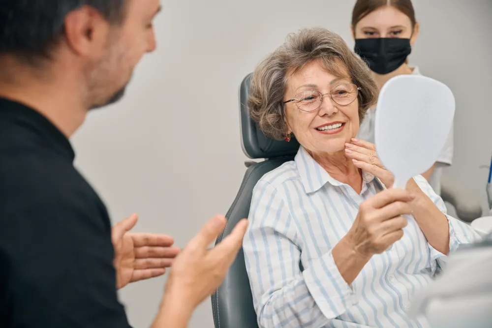 Patient admiring smile in mirror after treatment